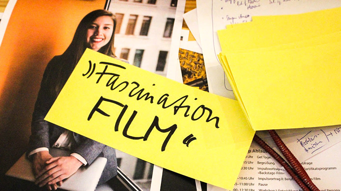 Detailausschnitt eines Fotos einer Dame auf dem ein Zettel klebt: "Faszination Film"