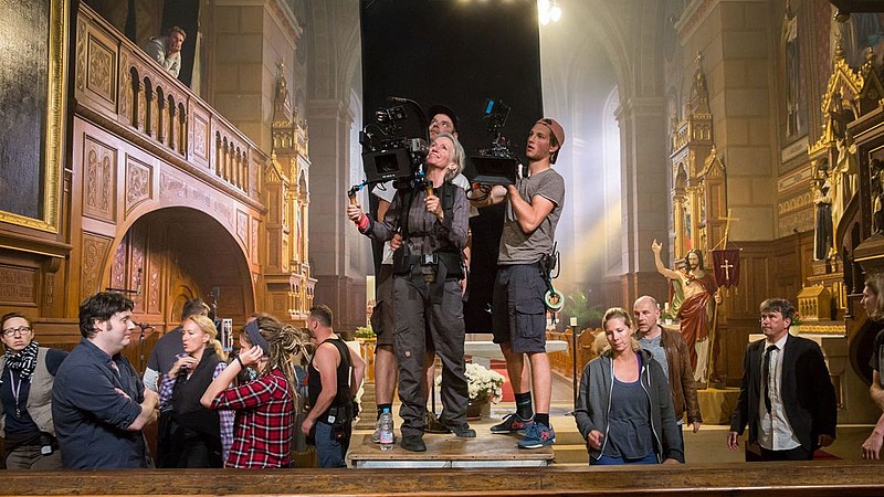 In einem Filmset steht eine Gruppe von Kameraleuten und hält Kameras in den Händen.